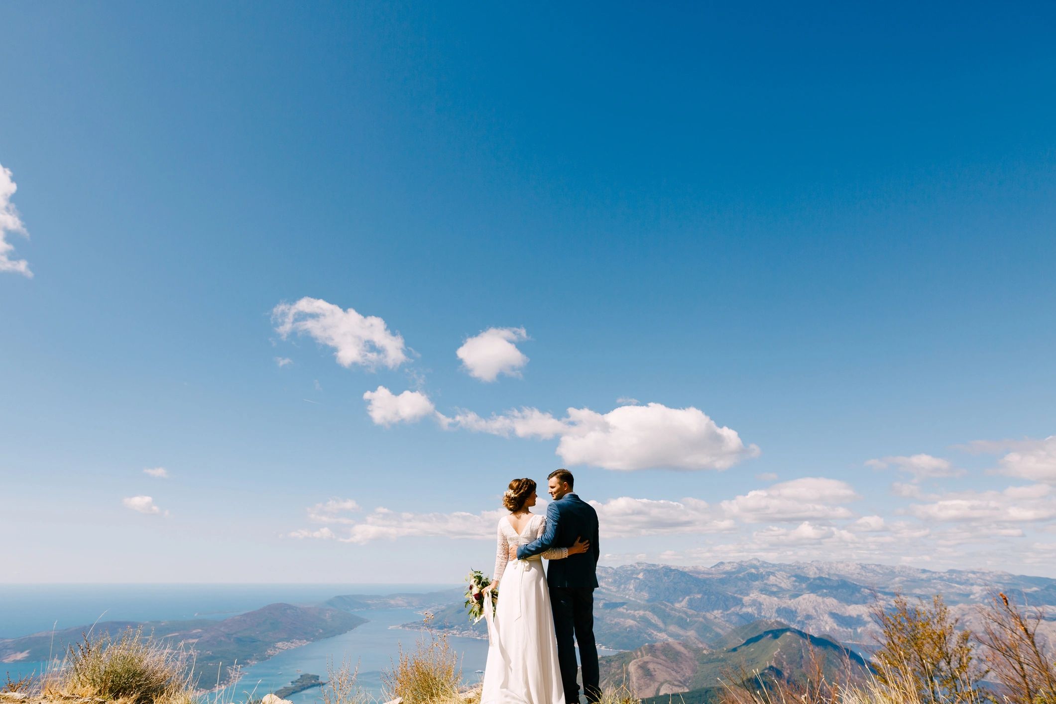 Newlyweds embracing with mountain backdrop