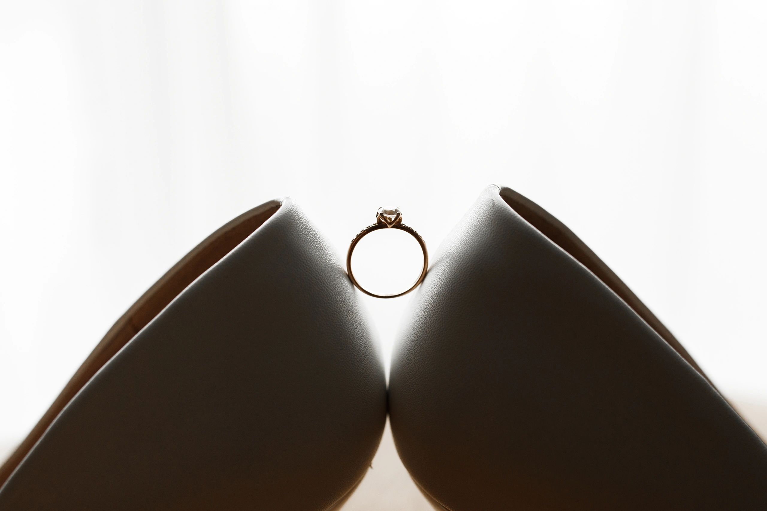 Wedding ring displayed between bridal shoes
